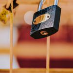 Detailed close-up of a rusty padlock on iron bars, showcasing the aged texture and selective focus.